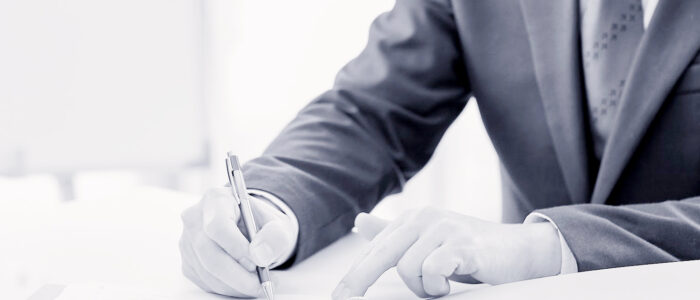 Hands signing a document with a pen.