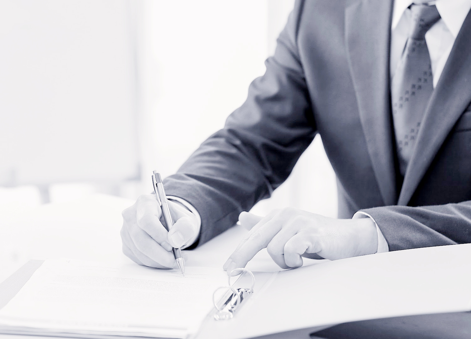 Hands signing a document with a pen.