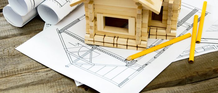 Building house. House construction. Many drawings for building and small wooden house on old wooden background.