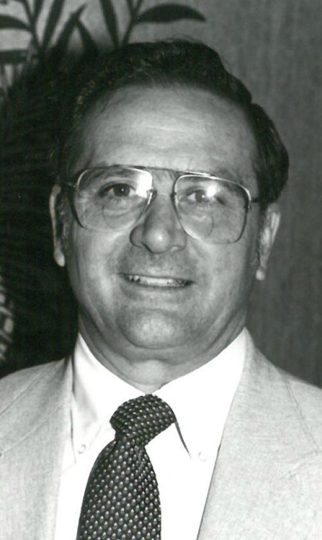 Man wearing glasses and a suit, smiling.