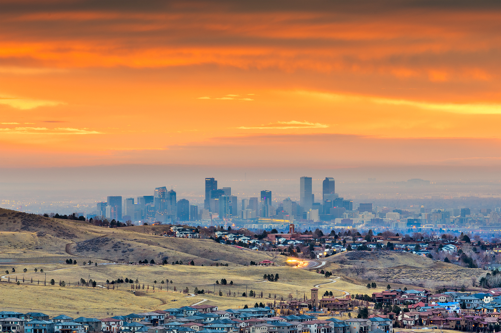 City skyline under vibrant orange sunset sky.