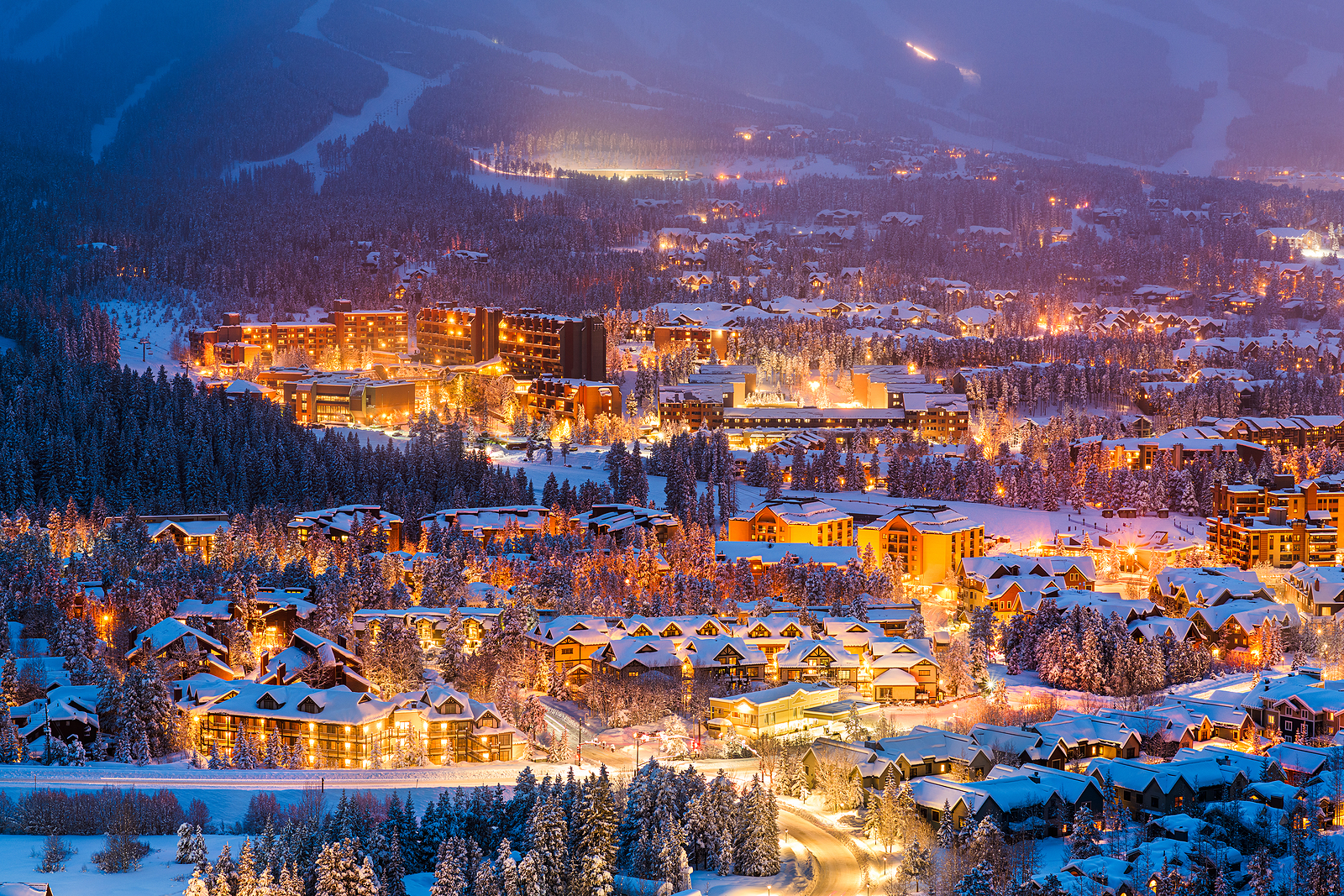 Snowy mountain town illuminated at night.